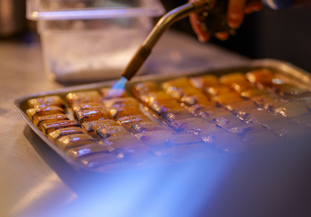 An Image of Tommy Banks preparing food at Signature Food Festival 2024